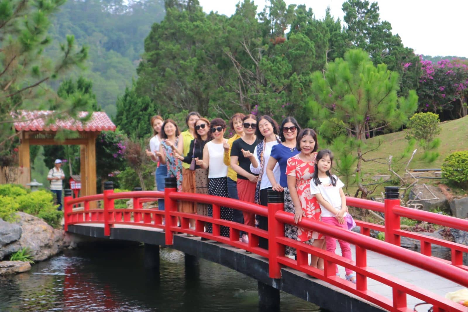 Du khách trên cầu đỏ bắc qua hồ cá koi